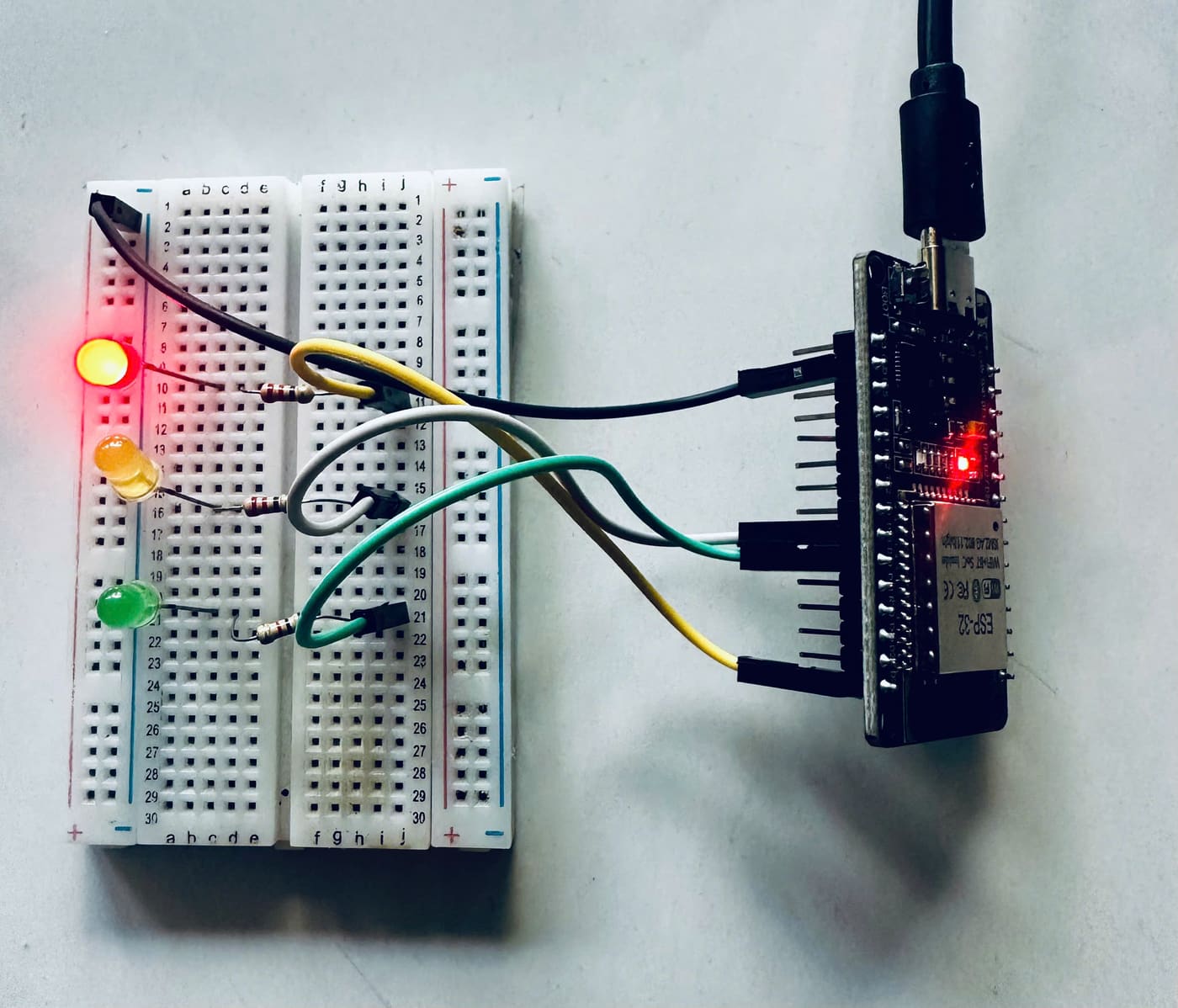Ảnh chụp mạch thật của Bài 3: ba LED đỏ, vàng, lục xếp dọc trên breadboard, mỗi LED một điện trở, bốn dây nối sang bo ESP32.